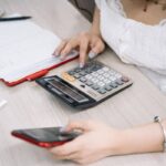 Femme manipulant une calculatrice et un smartphone sur une table de bureau