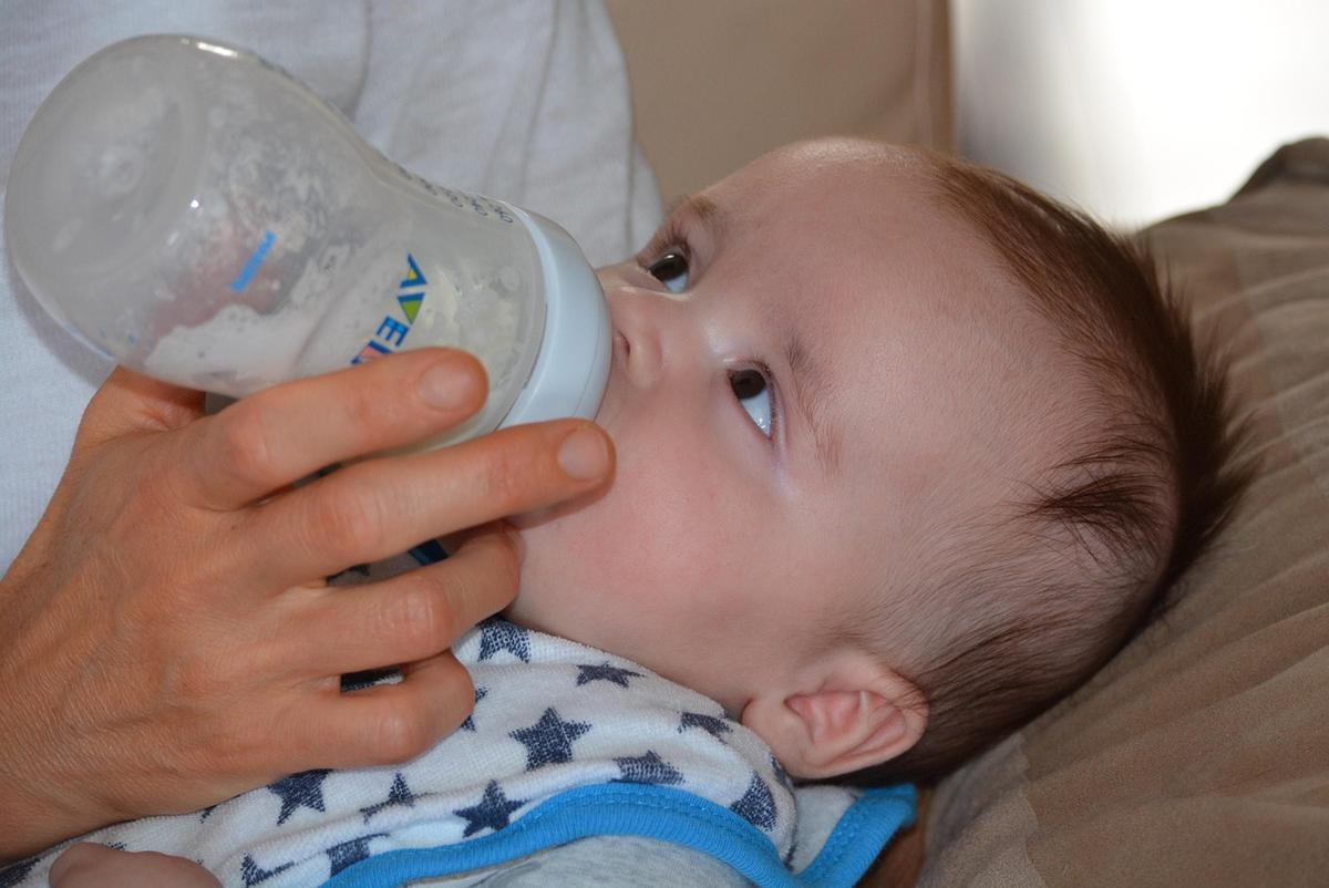 Un bébé reçoit du lait de la biberne, soutenu par une main Un bébé reçoit du lait de la biberne, soutenu par une main