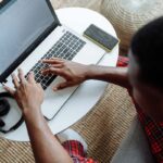 Homme utilisant un ordinateur portable avec écouteurs et tablette à côté