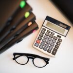 Calculatrice, lunettes, classeurs colorés sur un bureau