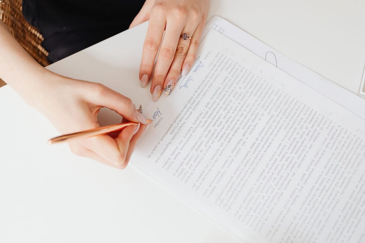 Une main écrit sur un document avec un stylo à une table
