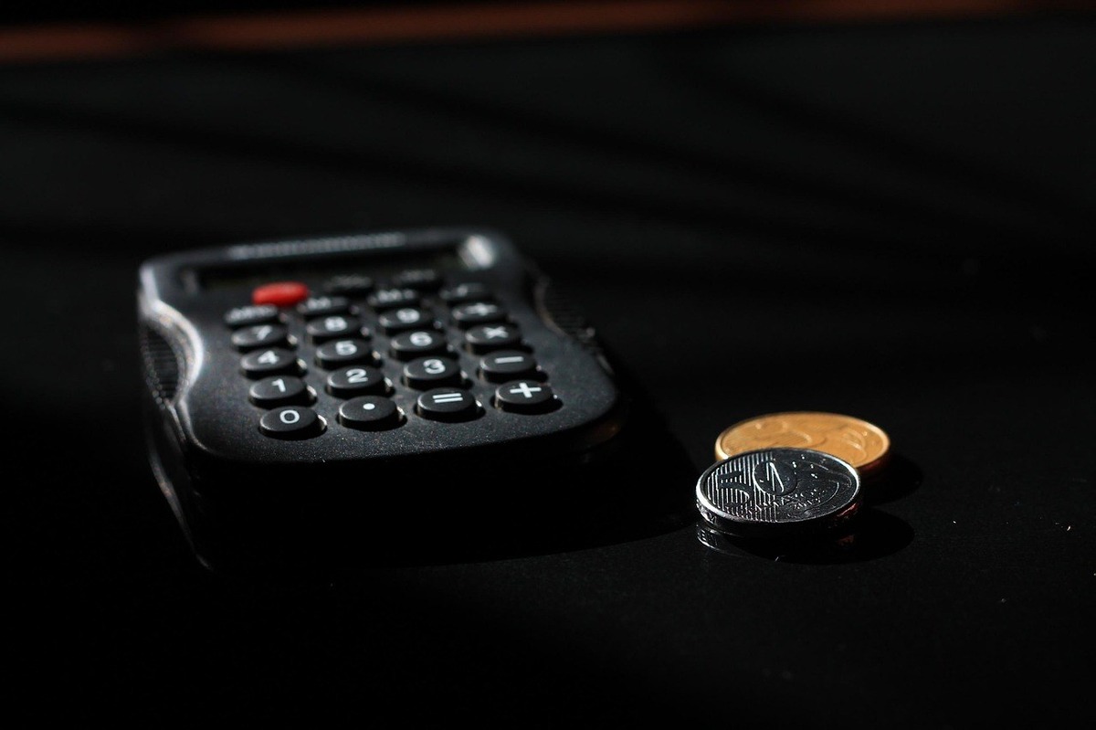 Calculatrice noire avec pièces de monnaie sur une surface sombre