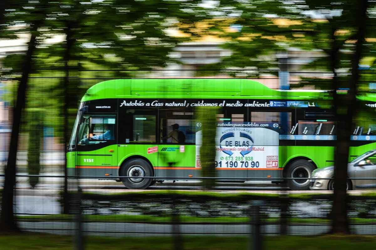 Bus vert circulant rapidement devant des arbres flous et une clôture Bus vert circulant rapidement devant des arbres flous et une clôture