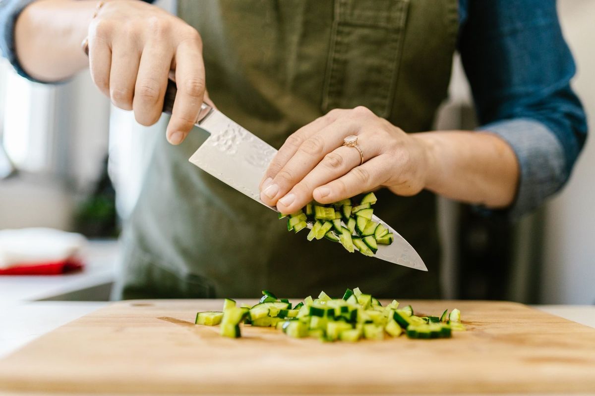 Personnage utilisant un couteau pour émincer des légumes verts sur une planche de bois
