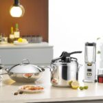 Ustensiles de cuisine, casserole, blender et petit électroménager sur plan de travail blanc de cuisine moderne