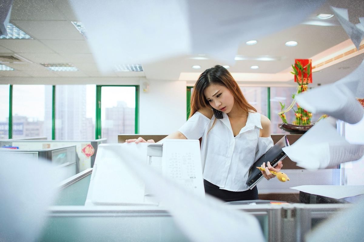 Femme en chemise blanche examine des documents dans un bureau moderne avec collègues Femme en chemise blanche examine des documents dans un bureau moderne avec collègues