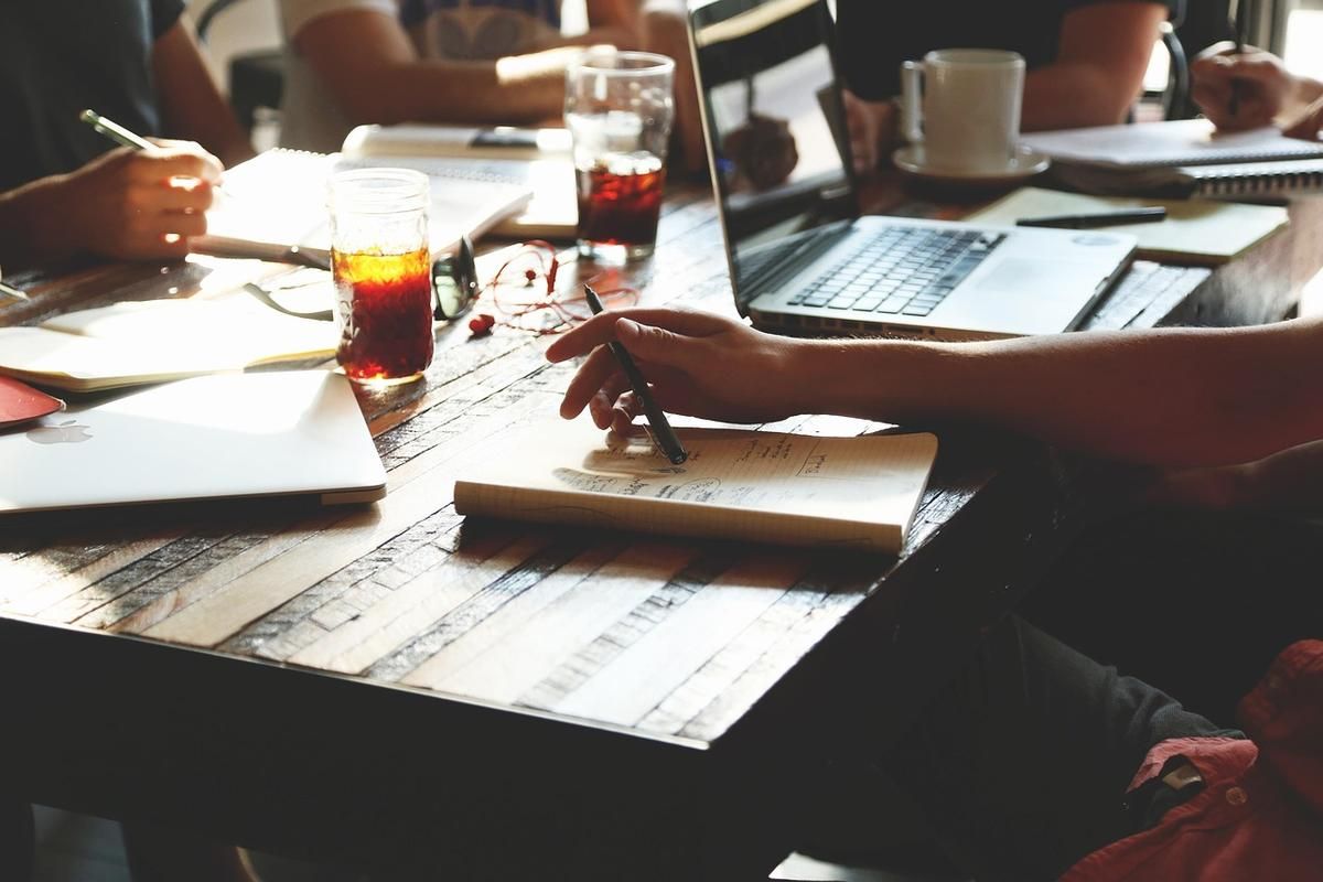 Groupe de personnes en réunion de travail autour d'une table avec documents et ordinateurs portables
