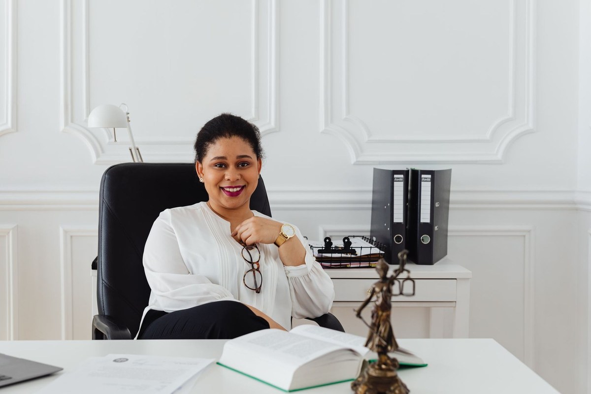 Femme souriante dans un bureau, devant un bureau avec livre et statue