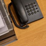 Un téléphone fixe posé sur un bureau en bois à côté d'un classeur